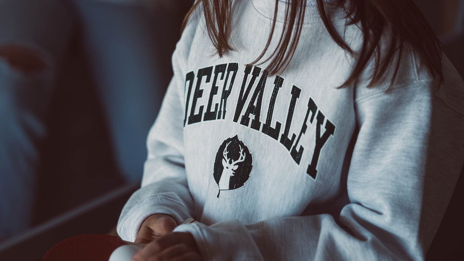 Young girl wearing a grey Deer Valley crew neck